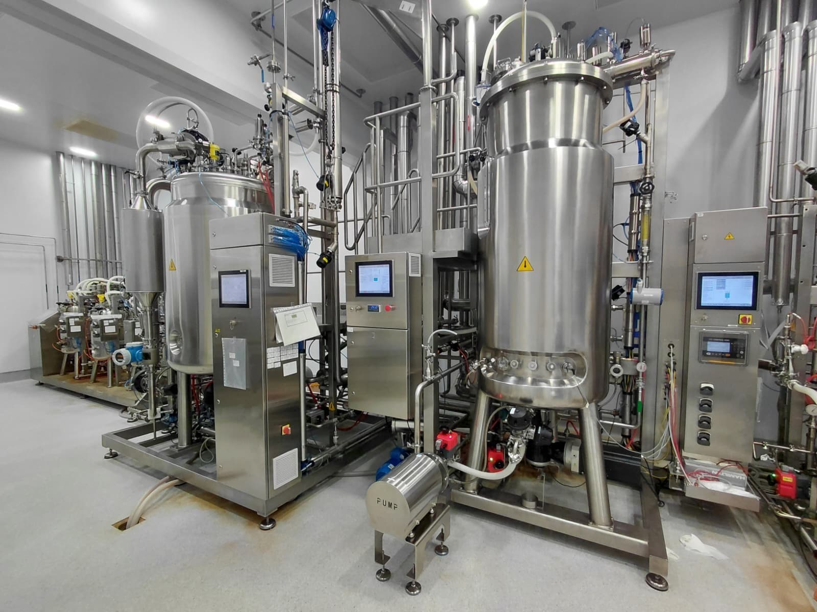 Stainless-steel bioreactor and tangential-flow filtration skid inside a biologics production plant.