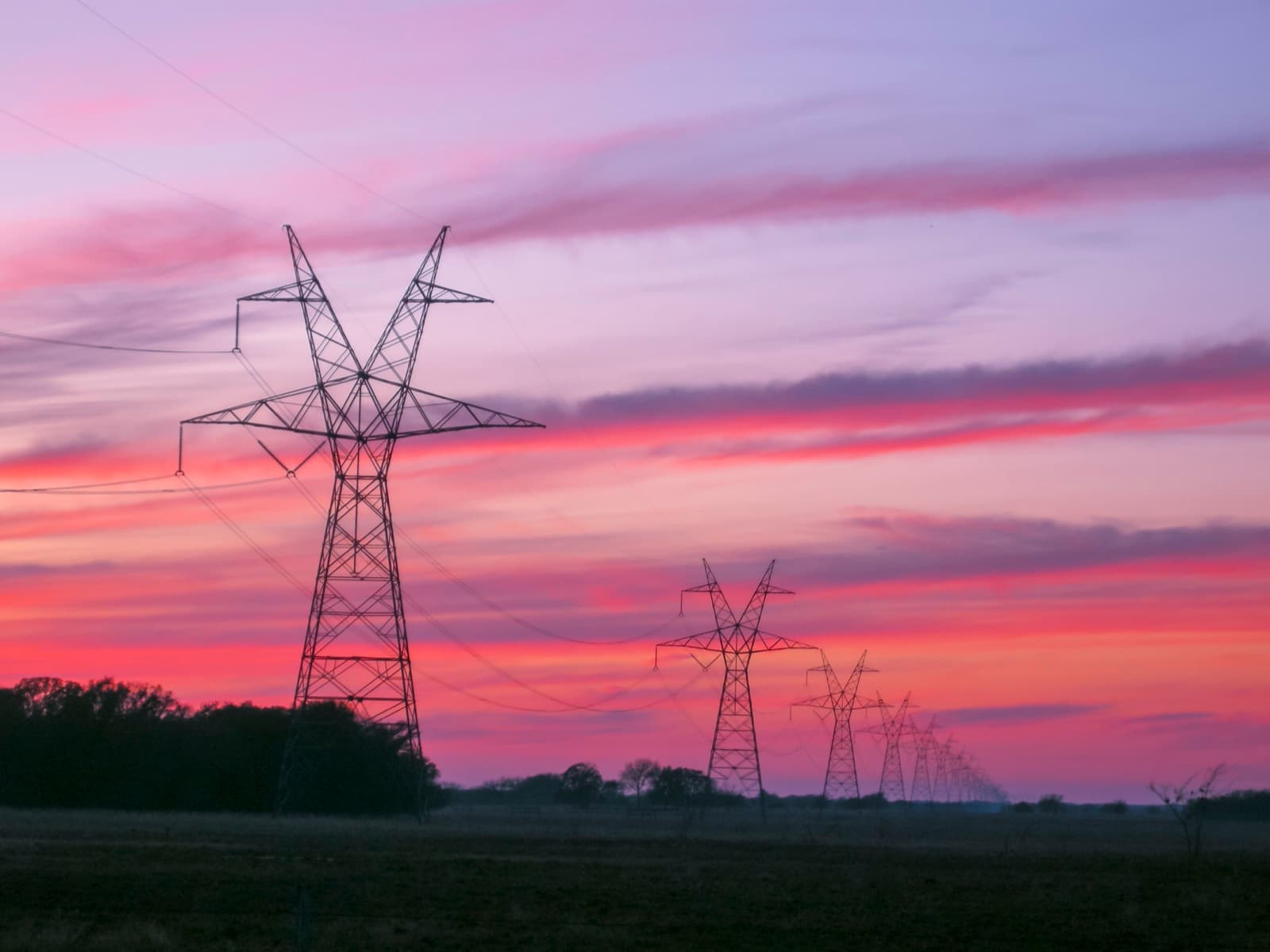 High-voltage transmission towers and power lines at sunset